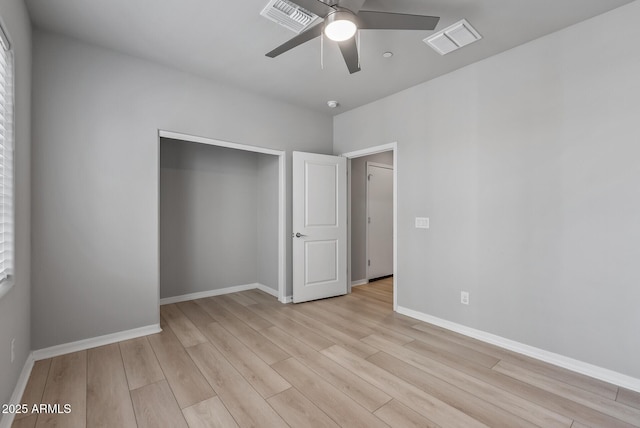 unfurnished bedroom featuring light wood-type flooring, a closet, visible vents, and baseboards