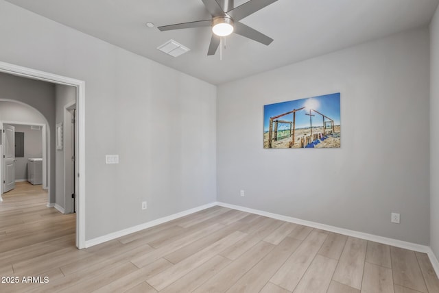 spare room featuring light wood-style floors, baseboards, arched walkways, and a ceiling fan