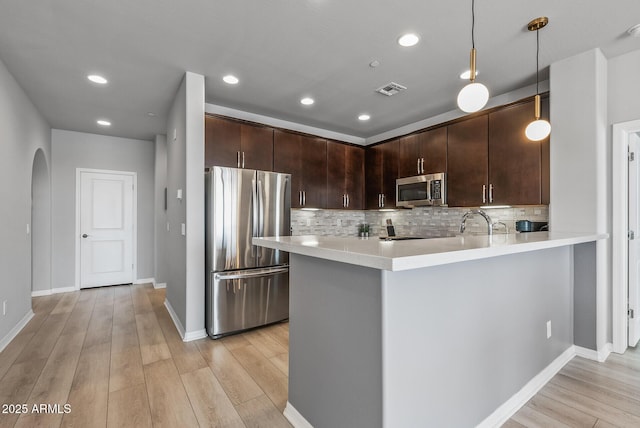 kitchen with dark brown cabinetry, stainless steel appliances, visible vents, light countertops, and light wood-type flooring