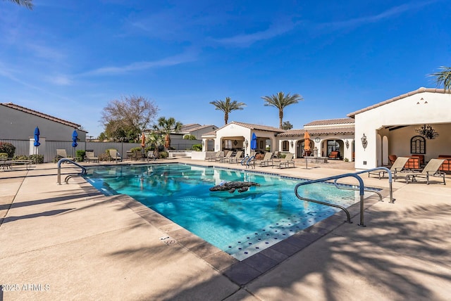 pool with a patio area and fence