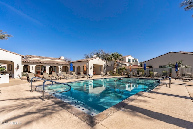 community pool with a patio and fence