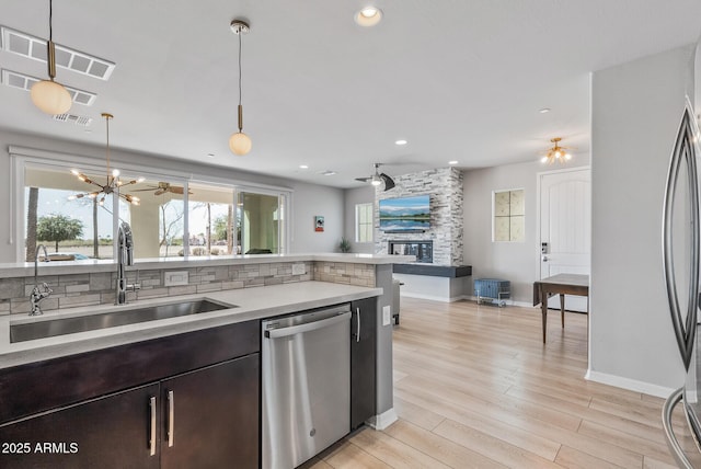 kitchen featuring appliances with stainless steel finishes, open floor plan, light countertops, light wood-type flooring, and a sink