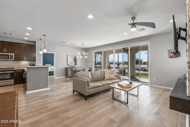 living area with light wood-style flooring, visible vents, baseboards, and ceiling fan