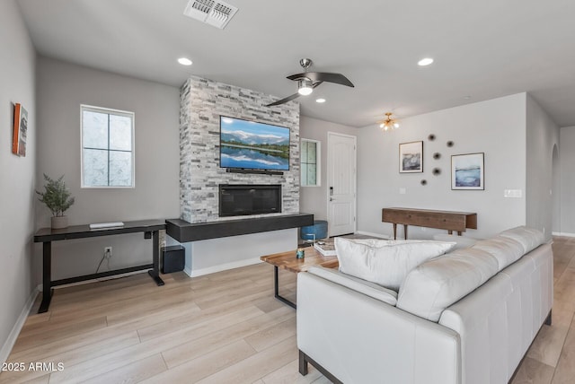 living area featuring light wood finished floors, recessed lighting, visible vents, and a stone fireplace