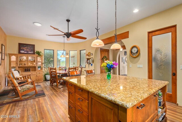 kitchen featuring black appliances, sink, hanging light fixtures, light wood-type flooring, and a kitchen island