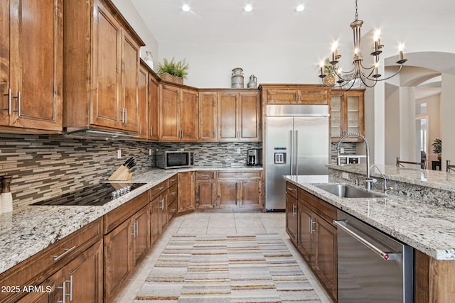 42429 N Cross Timbers Ct, Anthem, AZ 85086 - kitchen with appliances with stainless steel finishes, a sink, brown cabinetry, arched walkways, and recessed lighting