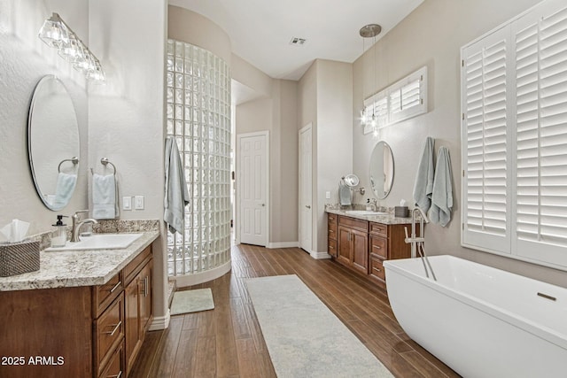 42429 N Cross Timbers Ct, Anthem, AZ 85086 - bathroom with wood finished floors, two vanities, a freestanding bath, and baseboards