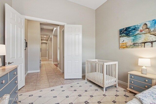 42429 N Cross Timbers Ct, Anthem, AZ 85086 - bedroom featuring arched walkways, a nursery area, light tile patterned flooring, and baseboards