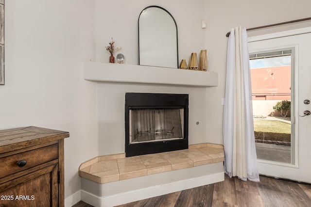 room details with wood finished floors, a fireplace with raised hearth, and baseboards