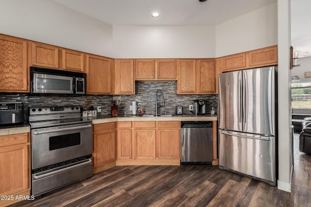 kitchen with a sink, stainless steel appliances, backsplash, and tile counters