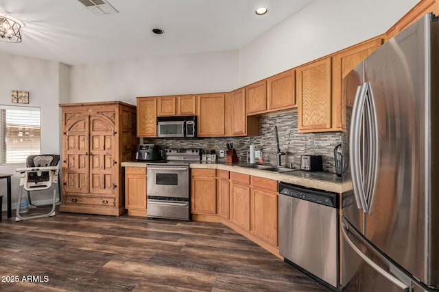 kitchen with visible vents, dark wood-style flooring, a sink, decorative backsplash, and appliances with stainless steel finishes