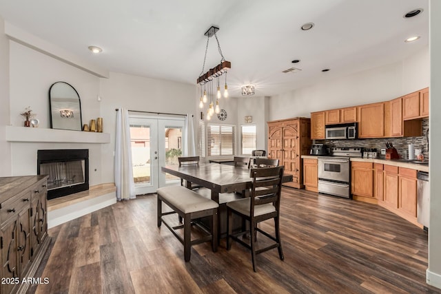 dining space with recessed lighting, a fireplace with raised hearth, french doors, and dark wood-style flooring