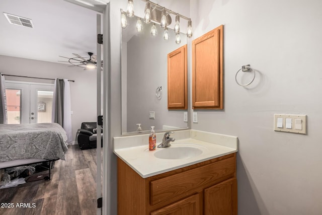 ensuite bathroom featuring vanity, wood finished floors, visible vents, ceiling fan, and french doors