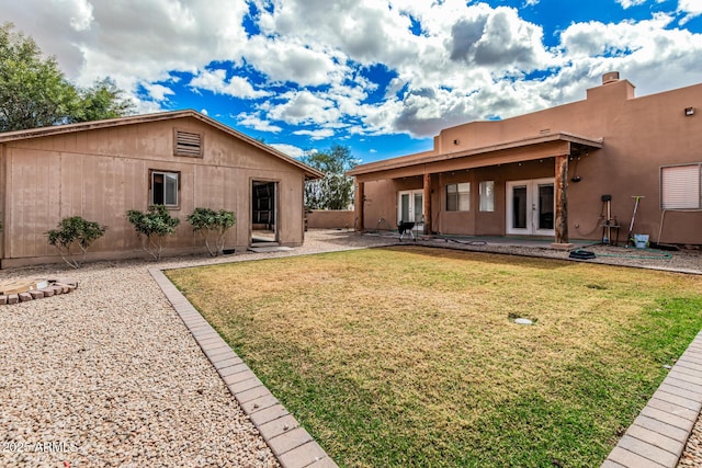 back of house with a patio area, a lawn, french doors, and stucco siding