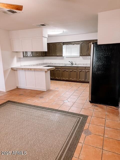 627 N H Ave, Douglas, AZ 85607 - kitchen featuring a peninsula, light countertops, freestanding refrigerator, light tile patterned flooring, and visible vents