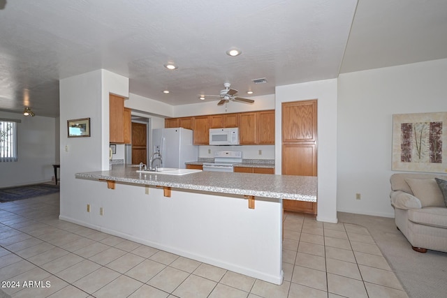 kitchen featuring kitchen peninsula, light tile patterned floors, a kitchen breakfast bar, ceiling fan, and white appliances