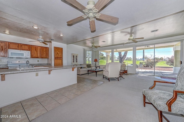 kitchen featuring white appliances, plenty of natural light, light tile patterned floors, and a textured ceiling