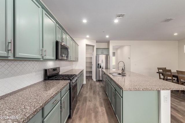 kitchen featuring green cabinets, appliances with stainless steel finishes, a kitchen island with sink, and sink