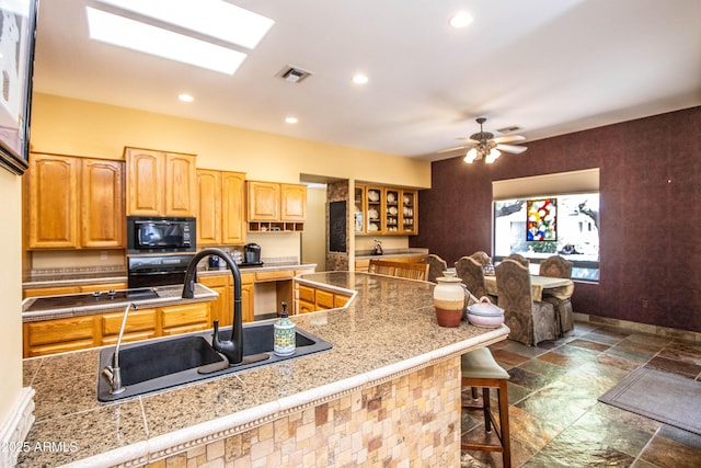 6334 E Albany St, Mesa, AZ 85205 - kitchen with black microwave, a sink, stone tile floors, a breakfast bar, and glass insert cabinets