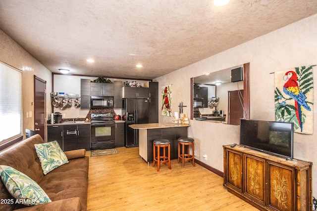 6334 E Albany St, Mesa, AZ 85205 - kitchen with black appliances, light wood-type flooring, a kitchen bar, a peninsula, and a sink