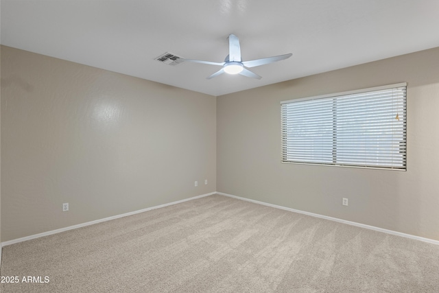 empty room featuring a ceiling fan, visible vents, carpet, and baseboards