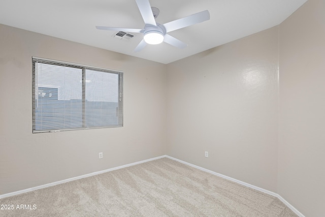 carpeted spare room featuring baseboards, visible vents, and ceiling fan