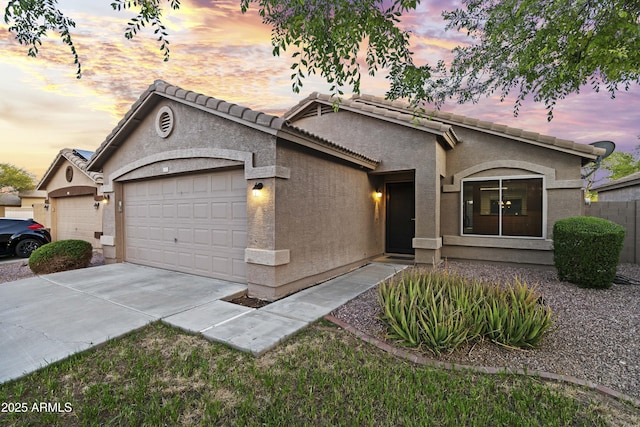 ranch-style home with a garage, stucco siding, a tile roof, and concrete driveway