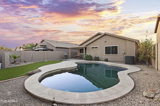 pool at dusk featuring a patio, a fenced backyard, central AC unit, and a fenced in pool