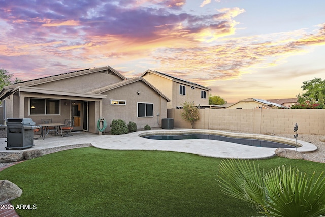 back of property with a patio area, stucco siding, a lawn, central AC, and a fenced backyard