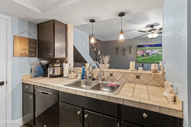 kitchen with pendant lighting, dishwasher, sink, ceiling fan, and a textured ceiling