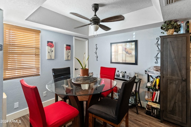 dining room with hardwood / wood-style floors, ceiling fan, a barn door, and a textured ceiling