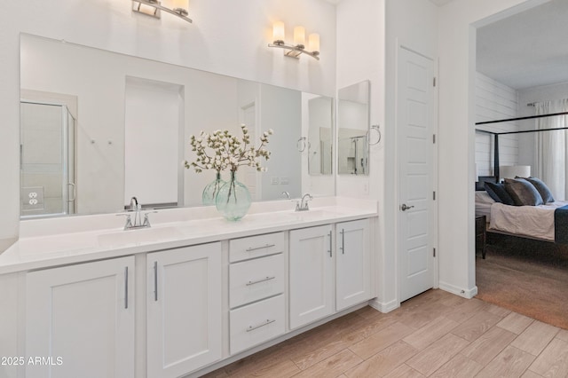 ensuite bathroom with a sink, ensuite bathroom, double vanity, and wood finished floors