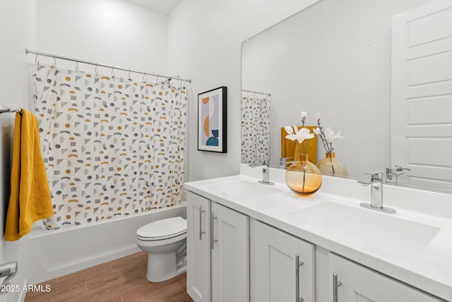 full bathroom featuring double vanity, toilet, a sink, and wood finished floors