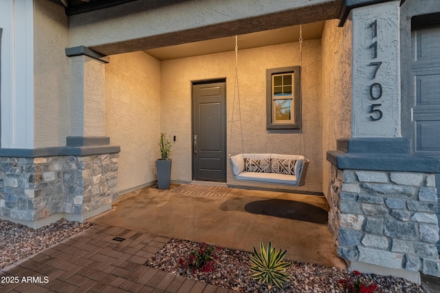 doorway to property featuring stucco siding and stone siding