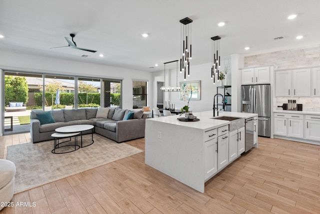 kitchen with a sink, light countertops, open floor plan, stainless steel appliances, and white cabinetry