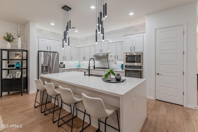 kitchen with tasteful backsplash, stainless steel appliances, light wood-type flooring, and a kitchen bar