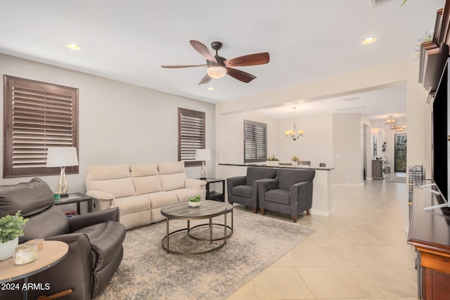 living room with light tile patterned flooring and ceiling fan with notable chandelier