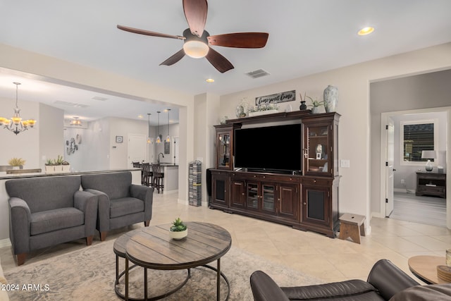 tiled living room featuring ceiling fan with notable chandelier