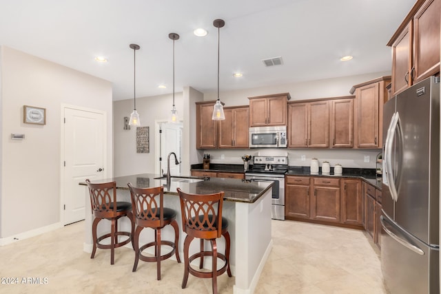 kitchen with a kitchen island with sink, sink, a kitchen bar, decorative light fixtures, and appliances with stainless steel finishes