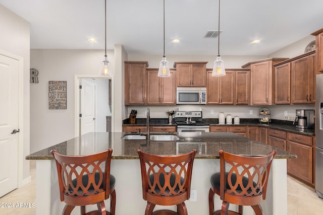 kitchen with decorative light fixtures, a kitchen island with sink, and stainless steel appliances