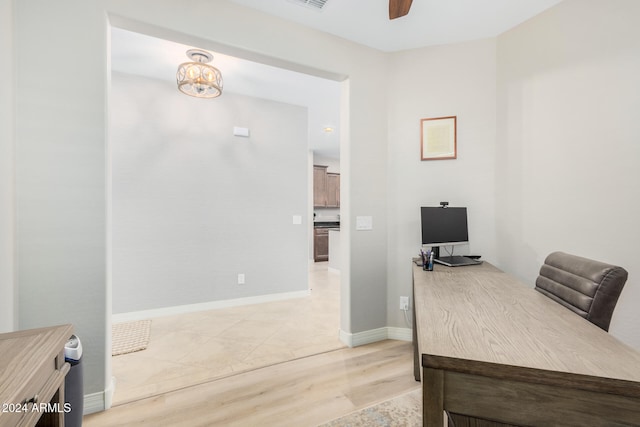 home office featuring light hardwood / wood-style floors and ceiling fan with notable chandelier