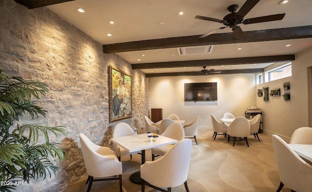 dining space with ceiling fan, light colored carpet, and beam ceiling