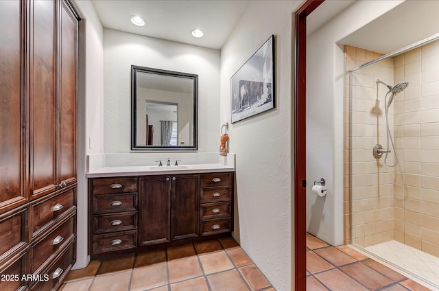 bathroom with tiled shower, vanity, and tile patterned flooring