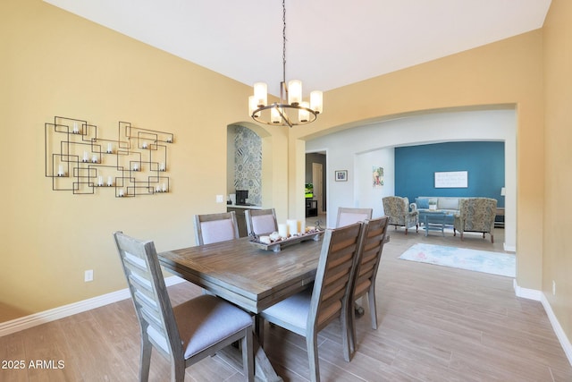 dining area with hardwood / wood-style flooring, lofted ceiling, and an inviting chandelier