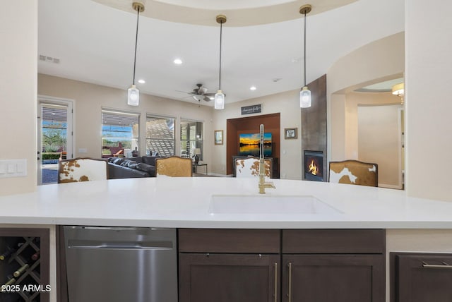 kitchen with ceiling fan, sink, stainless steel dishwasher, decorative light fixtures, and a fireplace