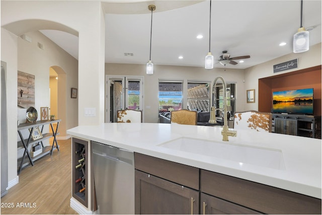 kitchen with light wood-type flooring, ceiling fan, sink, decorative light fixtures, and dishwasher