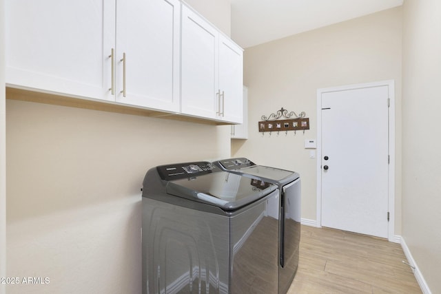 washroom featuring light hardwood / wood-style floors, cabinets, and washing machine and clothes dryer