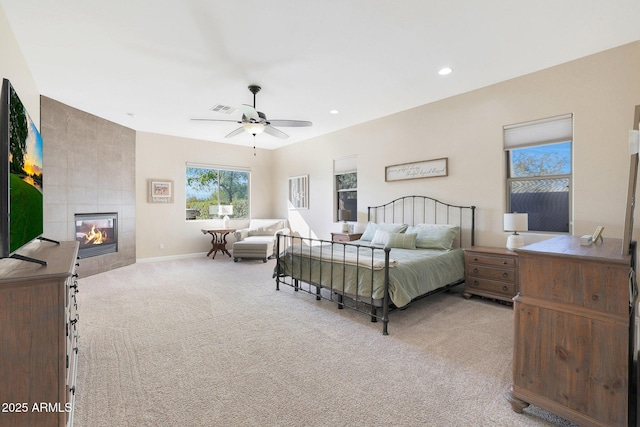 bedroom featuring ceiling fan, light colored carpet, and a fireplace