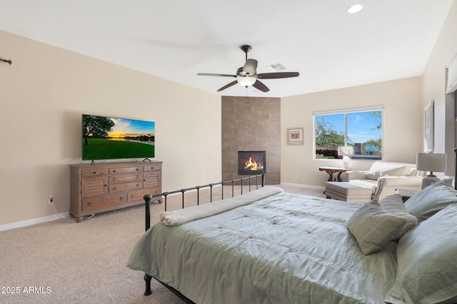 carpeted bedroom with a tile fireplace and ceiling fan