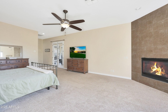 carpeted bedroom featuring ceiling fan and a tiled fireplace